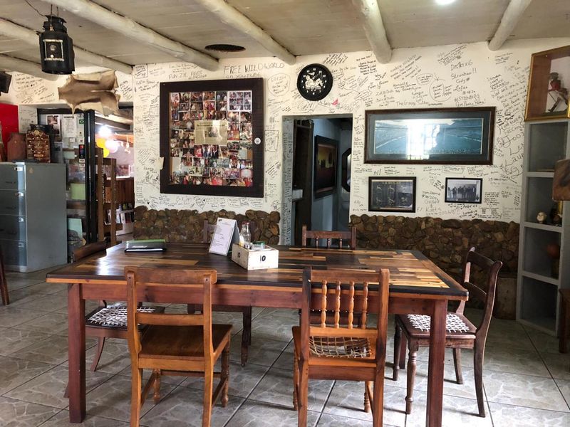 Dining area featuring stone wall accents, exposed beam ceiling, and tiled flooring, currently decorated with extensive wall writing.