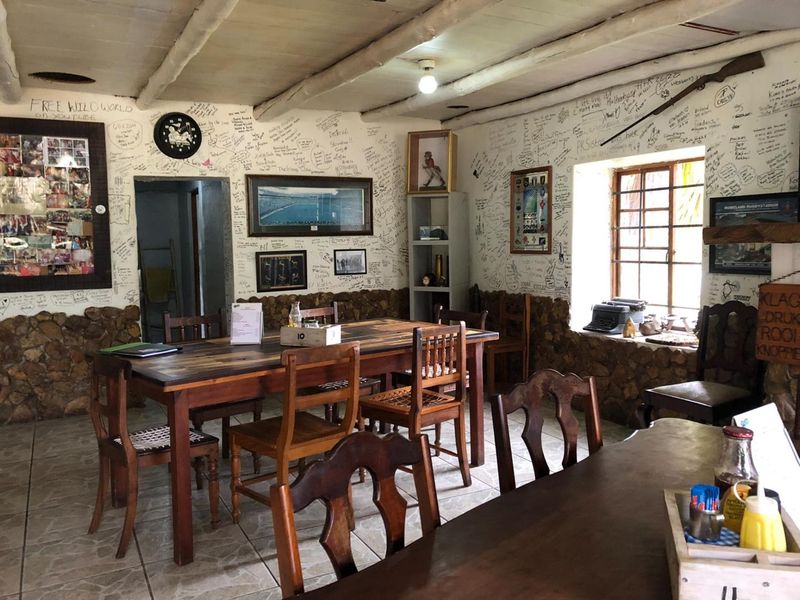 Rustic dining area featuring stone wainscoting, exposed beam ceilings, and tiled flooring, currently decorated with extensive wall writing.
