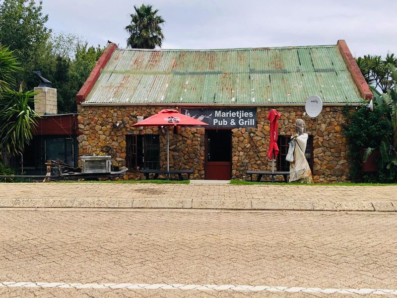 Front elevation of a commercial pub and grill featuring rustic stone masonry walls and a weathered corrugated metal roof.
