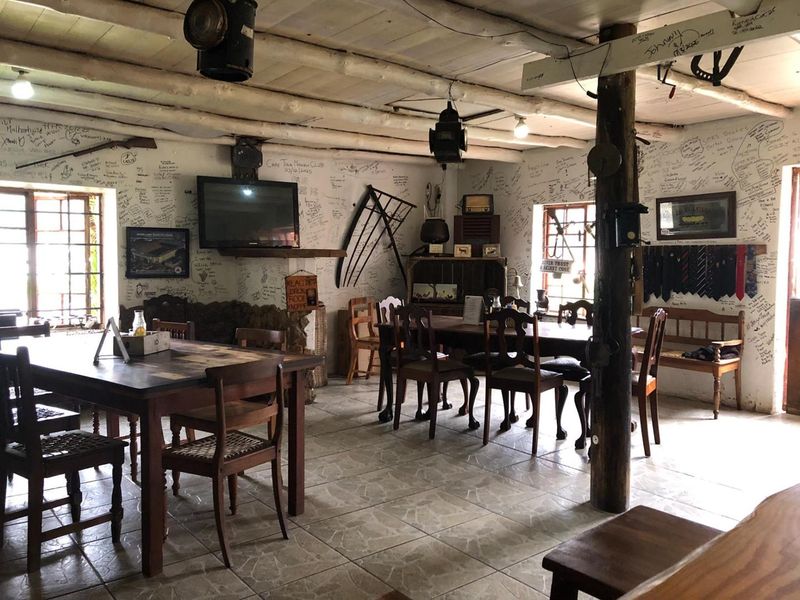 Rustic open-plan commercial space featuring exposed timber ceiling beams, tiled flooring, and a central timber support column, currently used as a dining area.