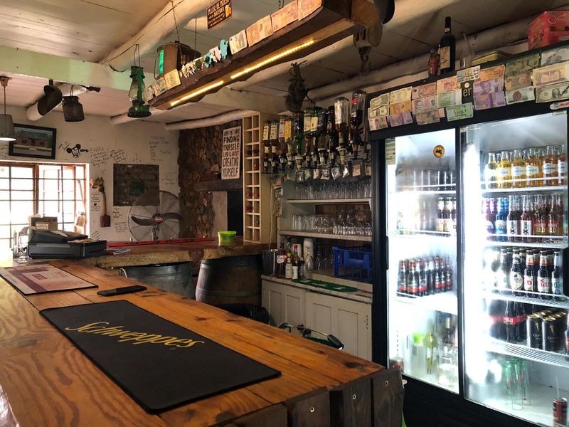 Rustic commercial bar area featuring a timber counter, stone accent wall, and integrated display refrigeration, offering a casual and established atmosphere.