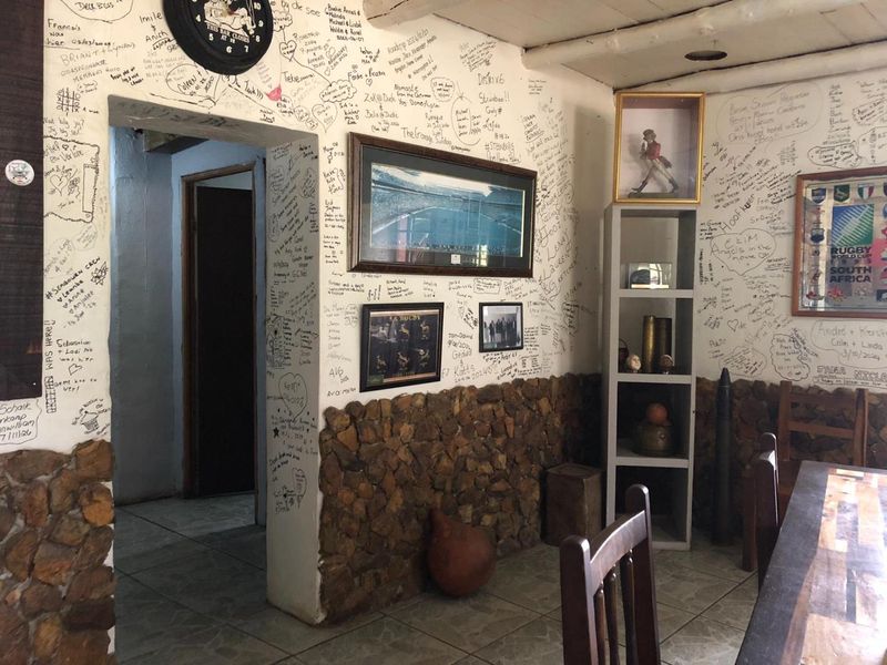A commercial bar area featuring stone wall cladding and tiled flooring, currently decorated with extensive wall writing and memorabilia.