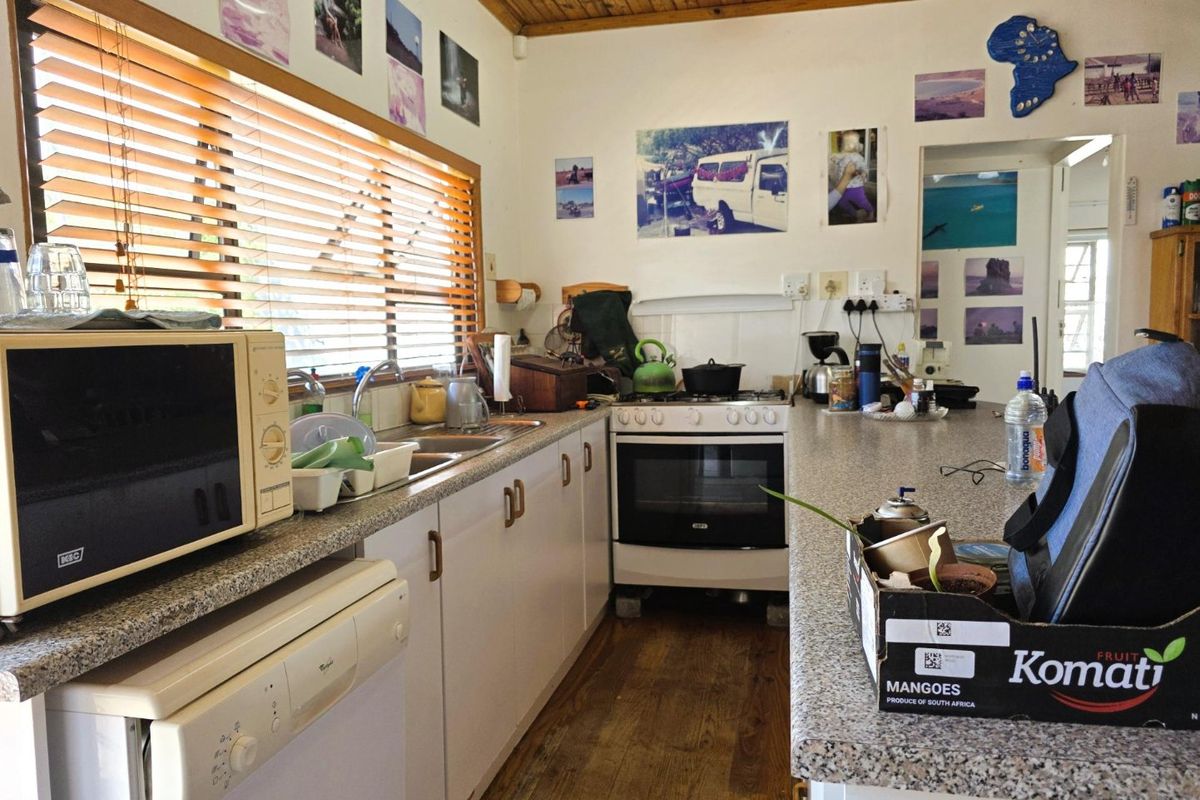 A functional kitchen featuring laminate countertops, built-in oven, hob, stainless steel sink, and timber ceiling finishes.
