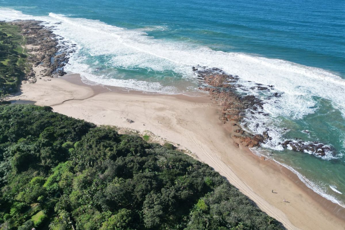 An aerial view showcasing the coastal landscape, sandy beach, and natural vegetation surrounding the property location.