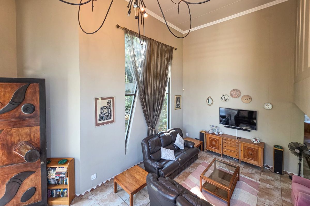 Spacious living room featuring high vaulted ceilings, tiled flooring, and a large, uniquely shaped feature window that provides ample natural light.