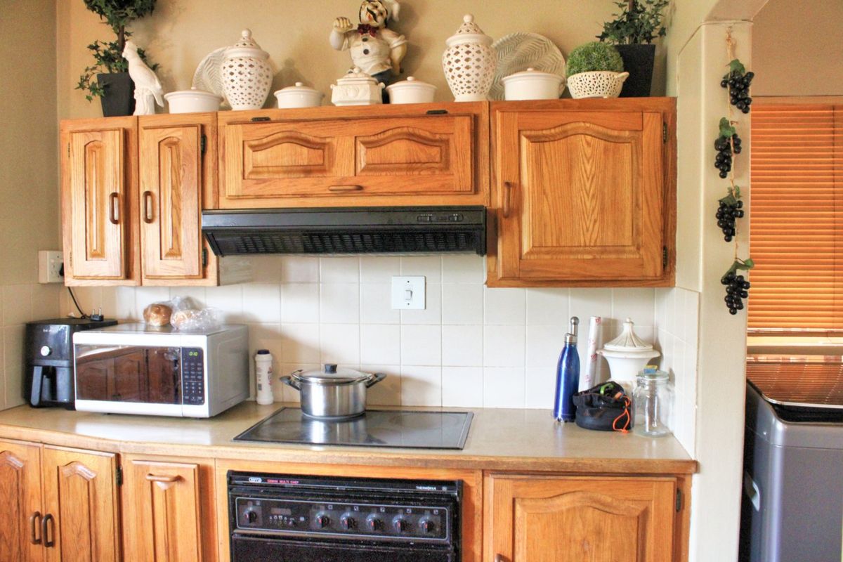 A functional kitchen featuring traditional wooden cabinetry, a ceramic tile backsplash, and integrated cooking appliances including an electric hob and oven.