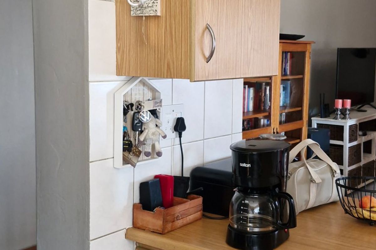A functional kitchen area featuring wood-look laminate cabinetry, tiled backsplash, and durable laminate countertops, offering a practical layout for daily use.