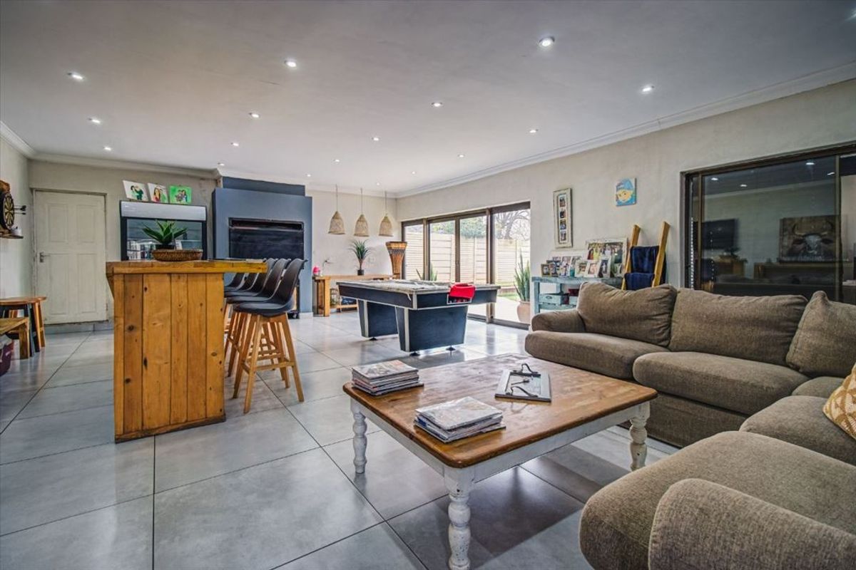 Spacious open-plan living area featuring large format floor tiles, recessed lighting, and sliding glass doors providing seamless access to the outdoor space.