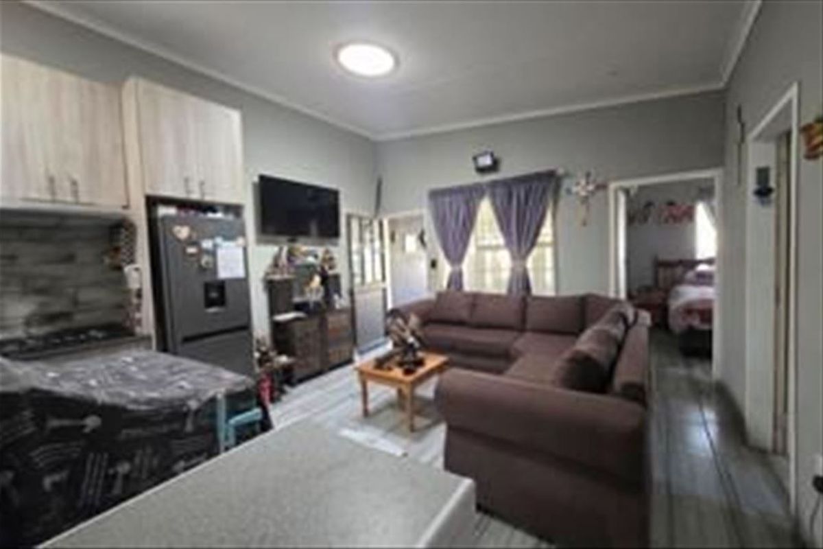 Open-plan living area featuring tiled flooring, built-in kitchen cabinetry, and direct access to adjacent rooms.