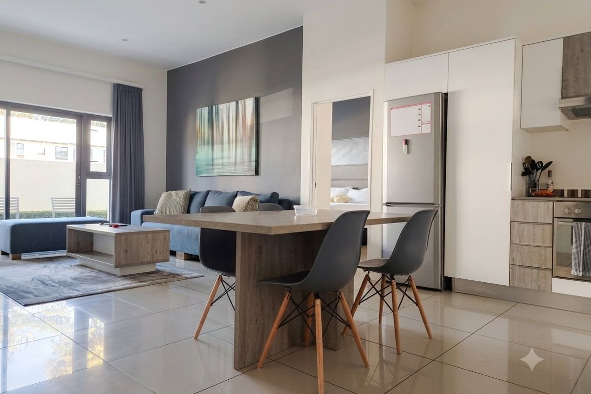 Modern open-plan living area featuring tiled floors, a contemporary kitchen with built-in appliances, and direct access to an outdoor patio through sliding glass doors.