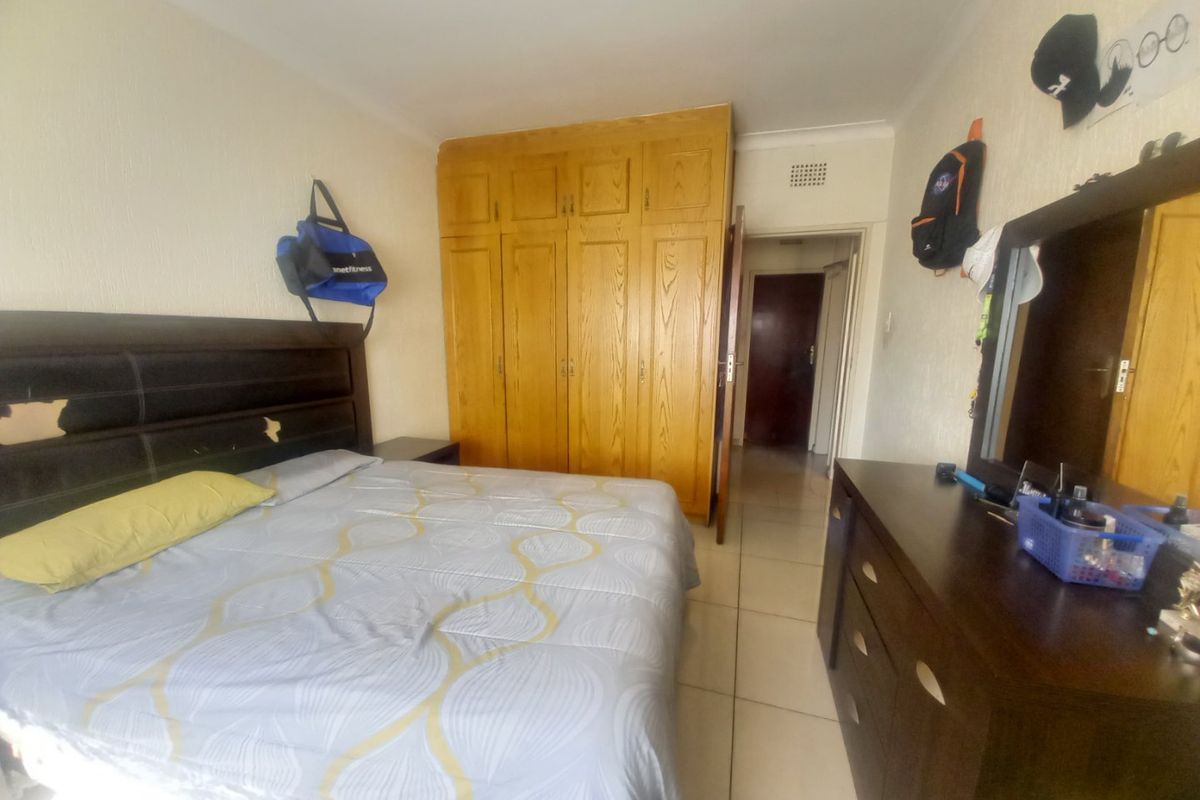 A bedroom featuring built-in wooden cupboards and tiled flooring, offering a functional space with potential for cosmetic updates.
