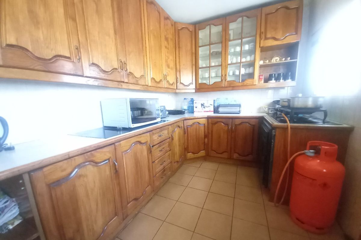 A functional kitchen featuring traditional wooden cabinetry, tiled flooring, and ample storage space, offering potential for a modern renovation.