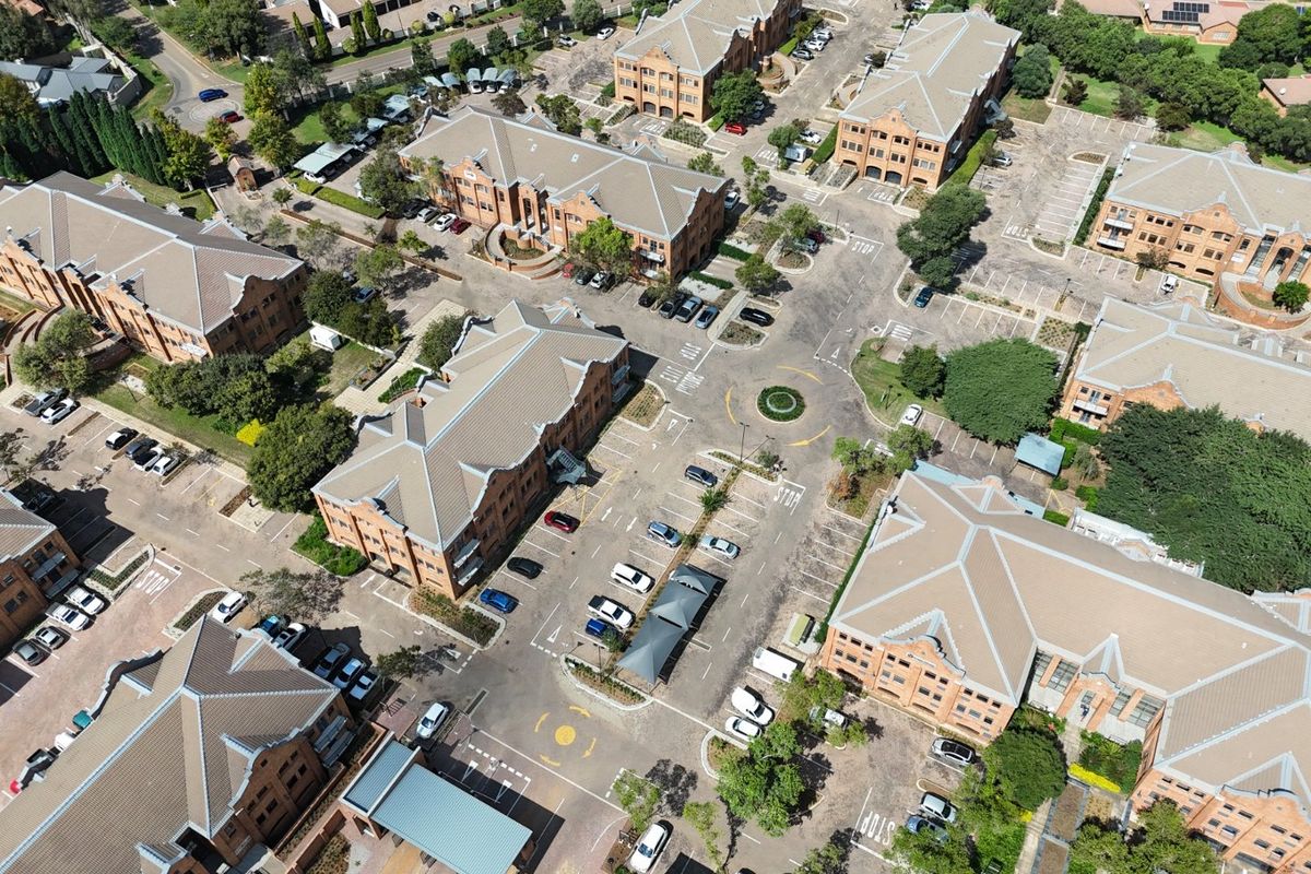 Aerial view of a commercial office park complex featuring multiple brick buildings, extensive parking facilities, and landscaped grounds.