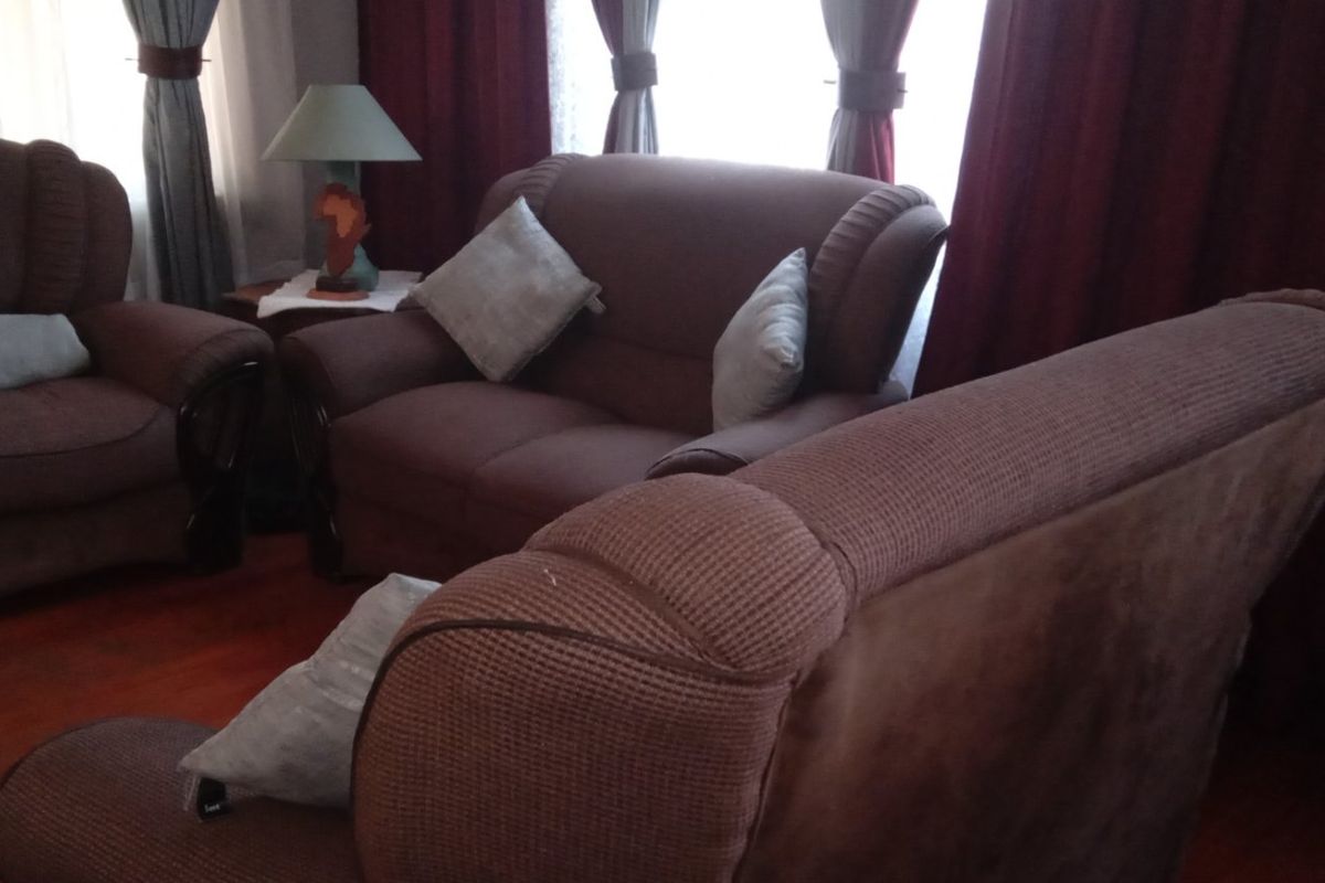 A living room area featuring laminate flooring and window treatments.