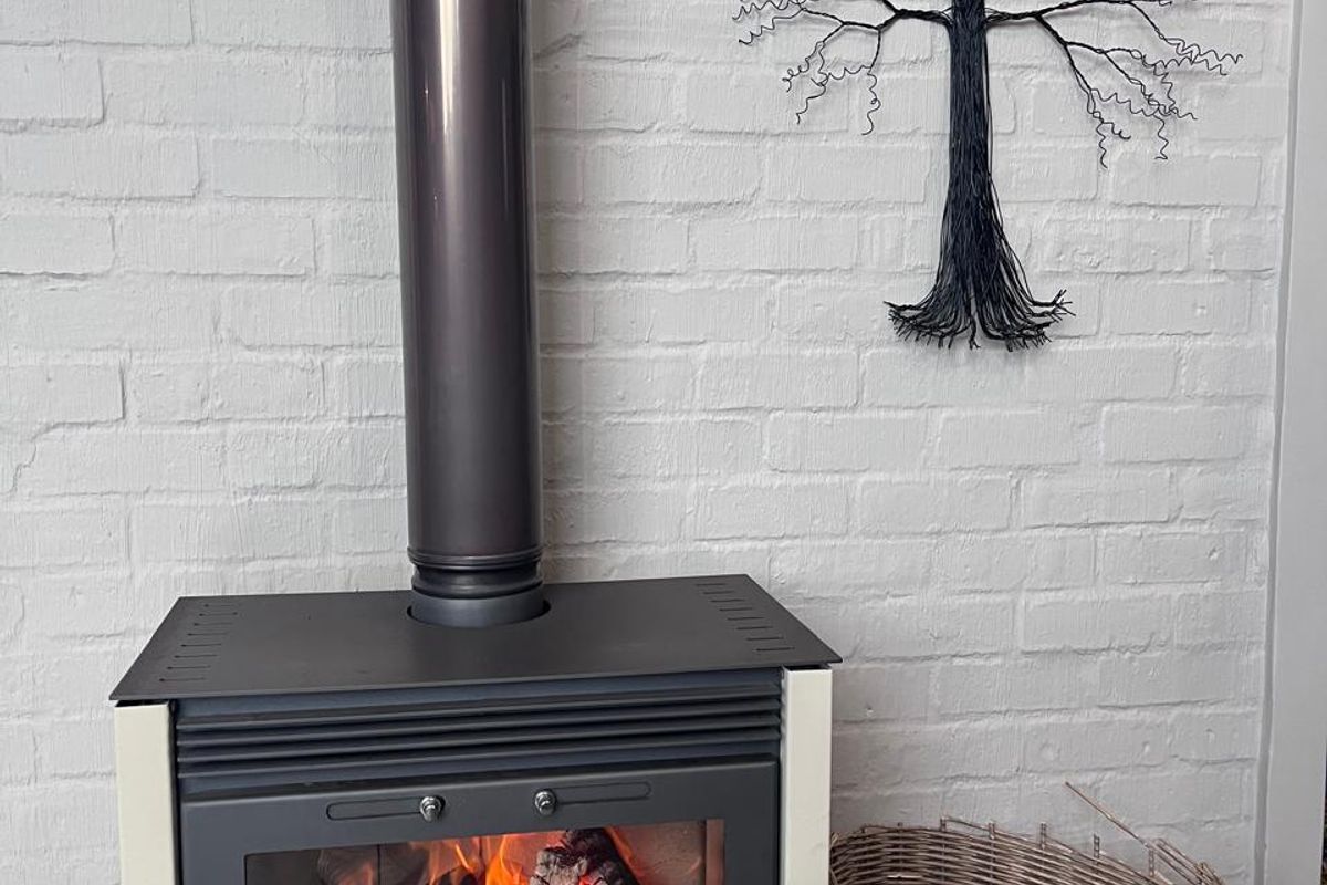 A cozy living area featuring a modern freestanding wood-burning fireplace set against a white painted brick wall.