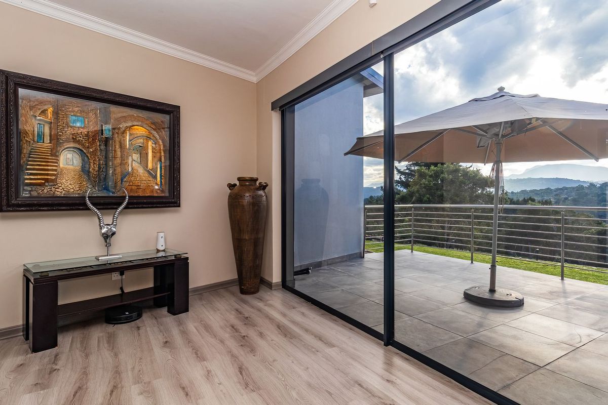 Bright living area featuring modern laminate flooring and large sliding glass doors that open onto a spacious tiled patio with scenic views.