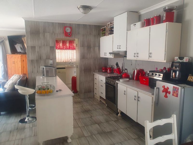 Open-plan kitchen featuring white cabinetry, tiled splashbacks, and a central island, seamlessly connecting to the adjacent living area.