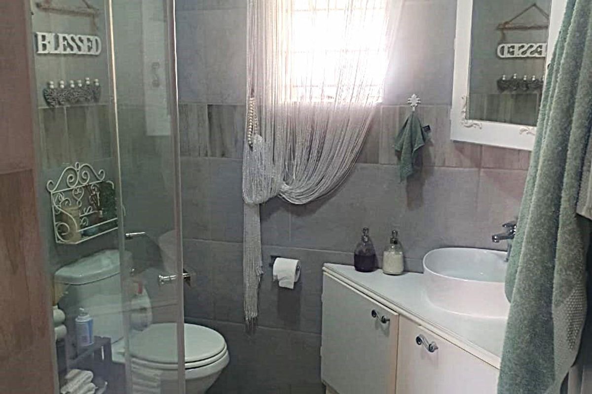 A functional bathroom featuring a glass shower enclosure, a white vanity cabinet with a vessel sink, and neutral wall and floor tiling.