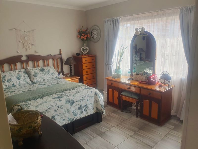 A well-lit bedroom featuring neutral wall tones and tiled flooring, providing a comfortable and functional living space.