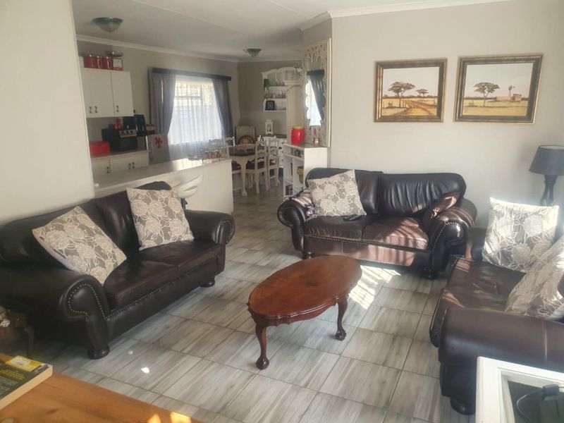 An open-plan living and kitchen area featuring tiled flooring, neutral walls, and a functional kitchen layout with a breakfast counter.