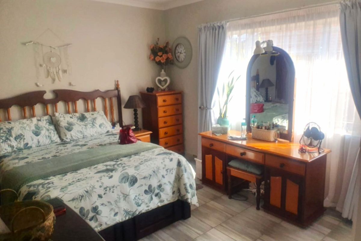 A well-lit bedroom featuring tiled flooring and large windows with curtain treatments, offering a comfortable and functional living space.