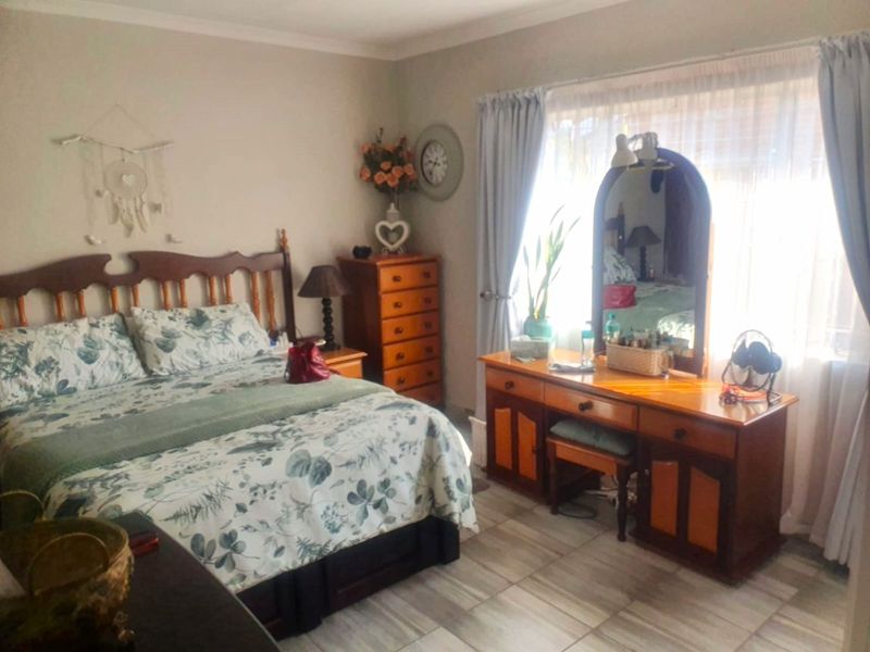 A well-lit bedroom featuring tiled flooring and large windows with curtain treatments, offering a comfortable and functional living space.