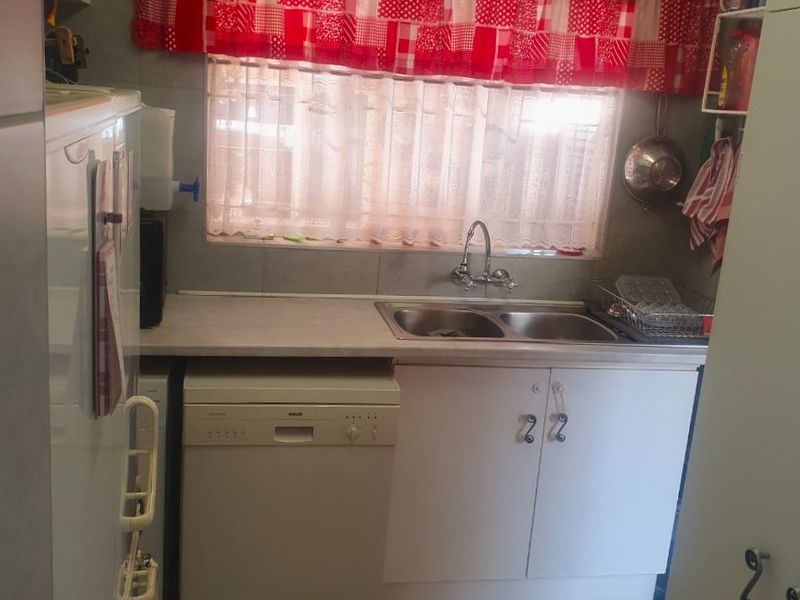 A functional scullery area featuring a double bowl sink, laminate countertops, built-in cabinetry, and tiled finishes.