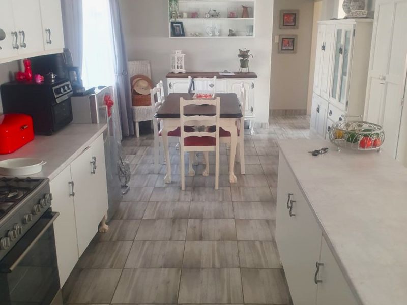 Open plan kitchen and dining area featuring tiled flooring, built-in cabinetry, and a central kitchen island.