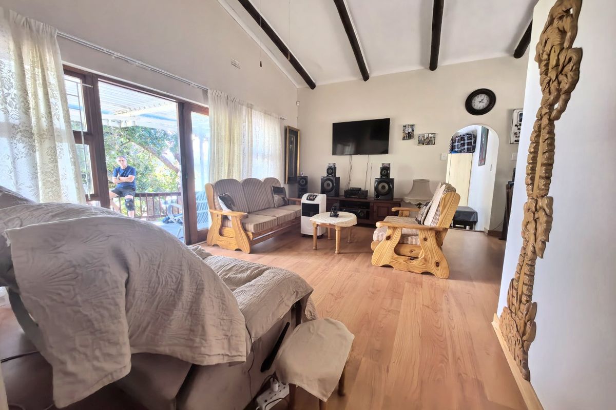 Spacious living room featuring exposed timber ceiling beams, laminate flooring, and large sliding glass doors providing access to the outdoor patio area.