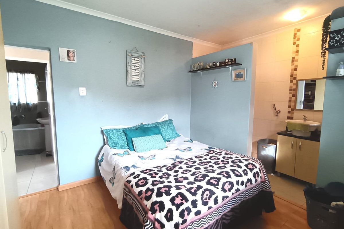 Bedroom featuring laminate flooring and an open-plan vanity area with a basin and tiled splashback.