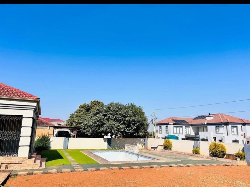 Outdoor pool area featuring a swimming pool, boundary wall, and a combination of artificial lawn and paved patio space.