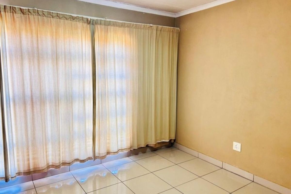 An empty living room featuring neutral tiled flooring and plain walls, offering a blank canvas for potential interior design updates.
