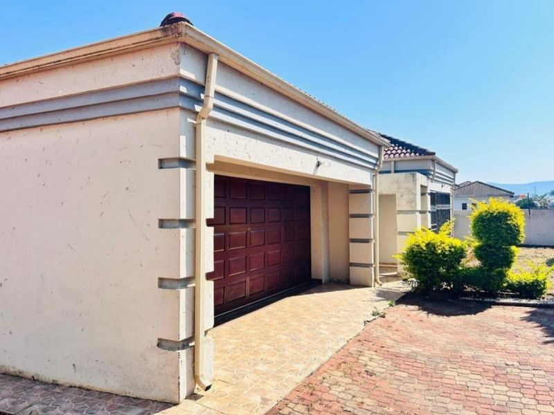 Front exterior view of the property featuring a single garage with a paved driveway and established garden area.