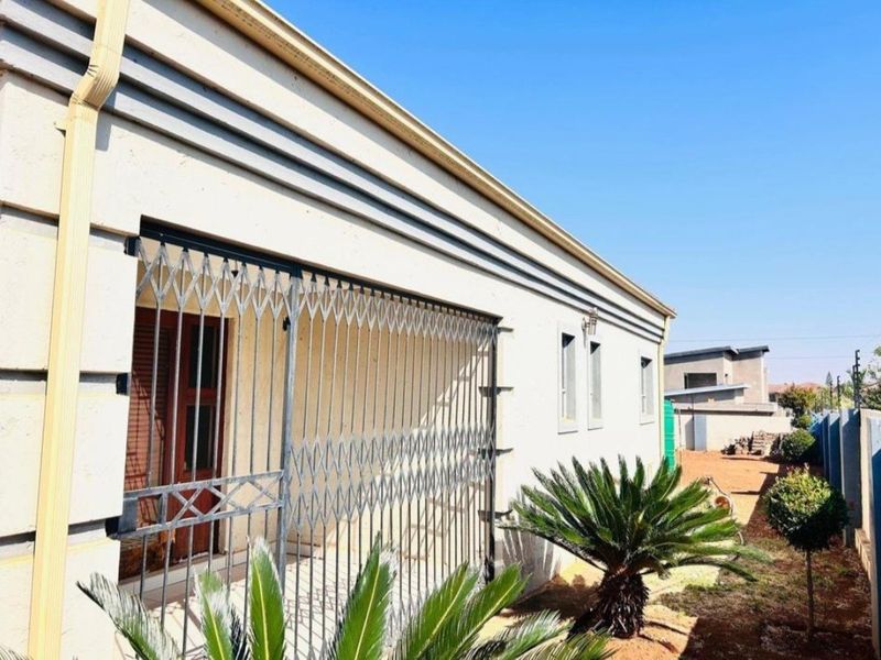 Rear exterior view of the property featuring a secure gated entrance and landscaped garden area.