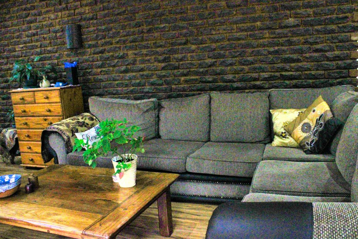 A living room featuring a textured dark exposed brick feature wall and wood-look laminate flooring.