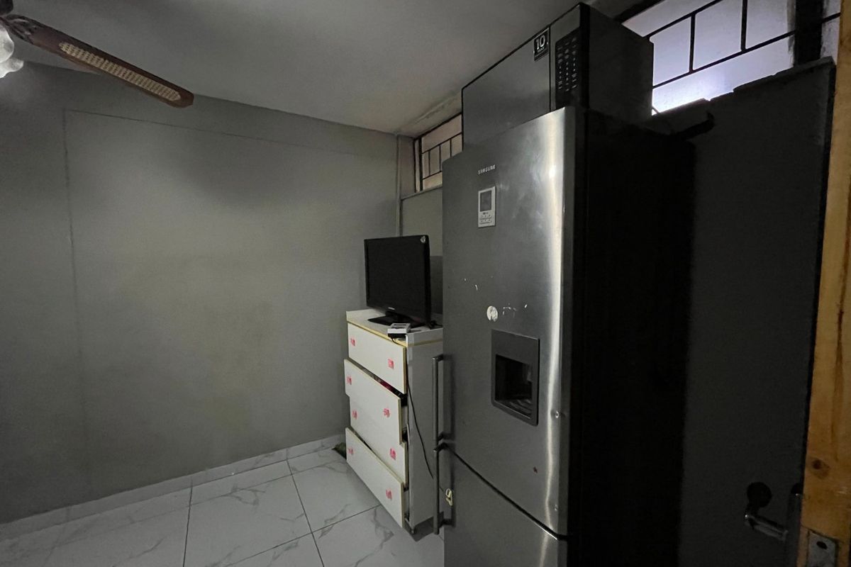 A small kitchen area featuring tiled flooring and a ceiling fan, currently utilized for appliance storage.