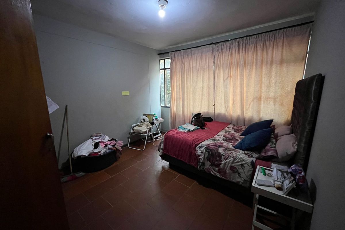 A bedroom featuring tiled flooring and large window with curtain tracks, requiring cosmetic updates to improve the overall aesthetic and appeal.