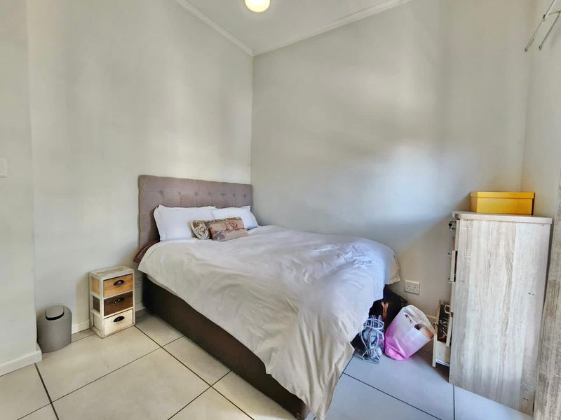 A compact bedroom featuring neutral wall finishes and tiled flooring, providing a functional space for a single or double bed setup.