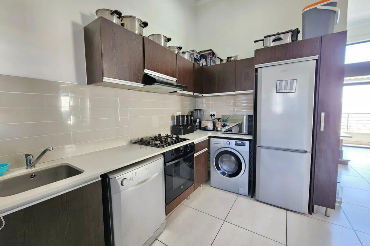 A functional kitchen featuring dark wood cabinetry, a gas hob, electric oven, extractor fan, and tiled backsplash with integrated appliance spaces.