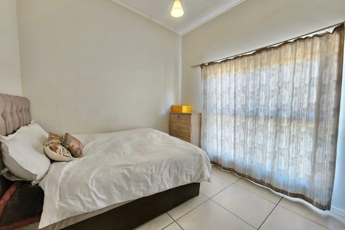A bedroom featuring neutral tiled flooring and simple ceiling cornicing, providing a clean and functional space.