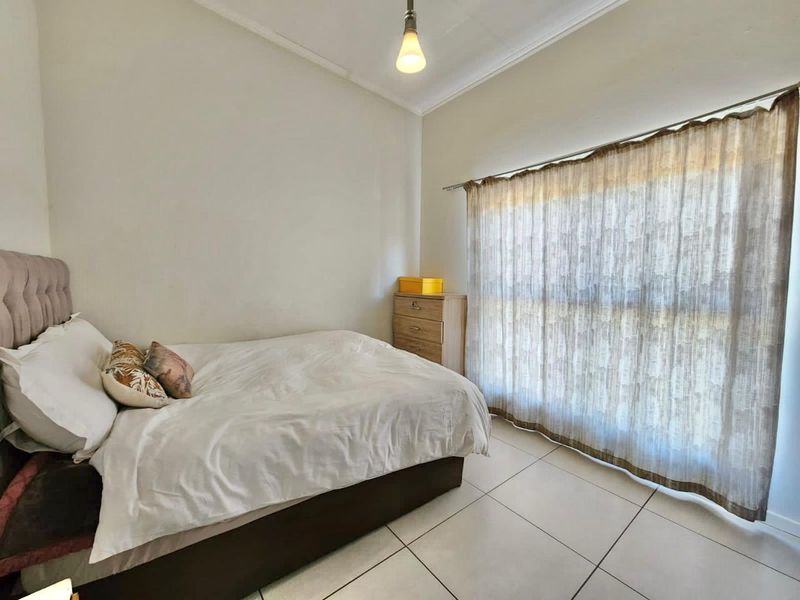 A bedroom featuring neutral tiled flooring and simple ceiling cornicing, providing a clean and functional space.