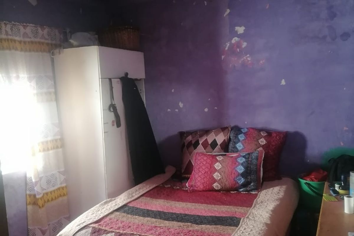 A bedroom featuring a built-in wardrobe, currently requiring significant cosmetic repairs to the walls and ceiling.