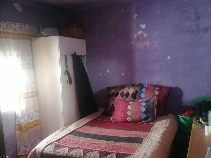 A bedroom featuring a built-in wardrobe, currently requiring significant cosmetic repairs to the walls and ceiling.