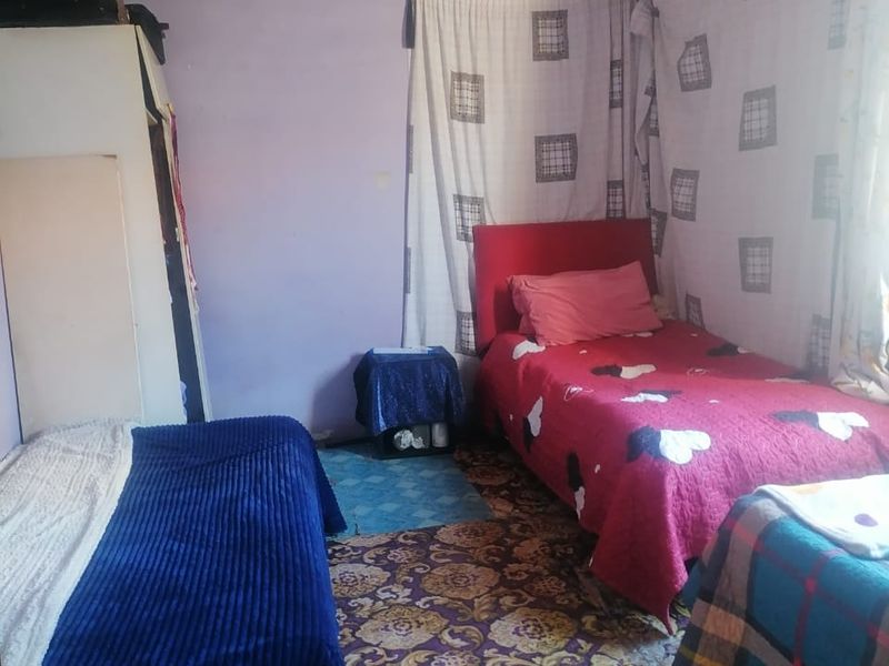A bedroom featuring a built-in wardrobe, requiring cosmetic updates to the wall finishes and flooring to improve the overall condition.