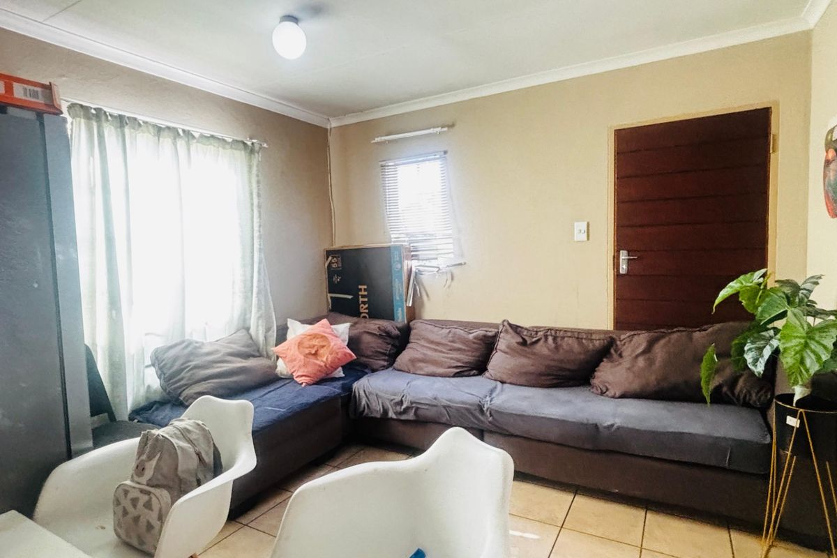 A living room area featuring tiled flooring, neutral wall finishes, and a timber door, providing a functional space for relaxation.