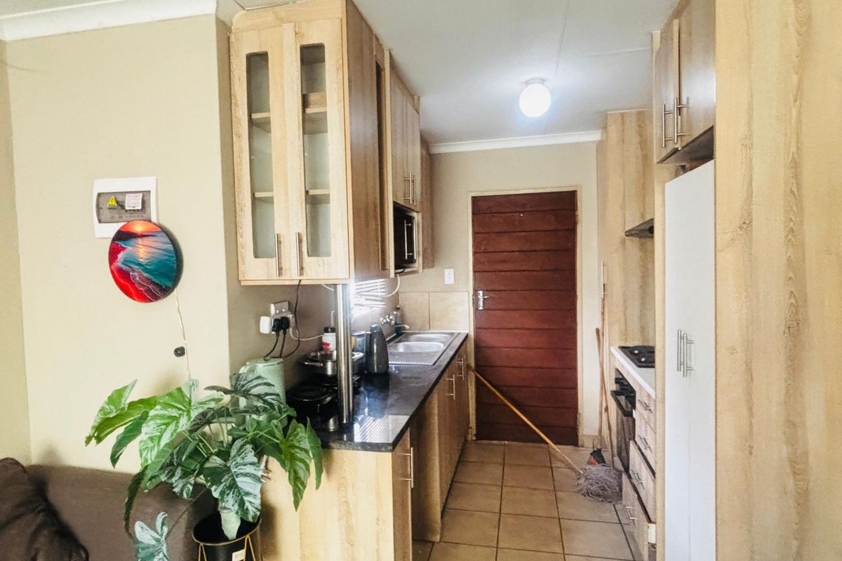 A functional kitchen featuring light wood cabinetry, granite countertops, built-in oven and hob, and tiled flooring.