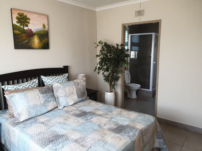 A bedroom featuring tiled flooring and an adjoining en-suite bathroom with a shower enclosure and toilet.