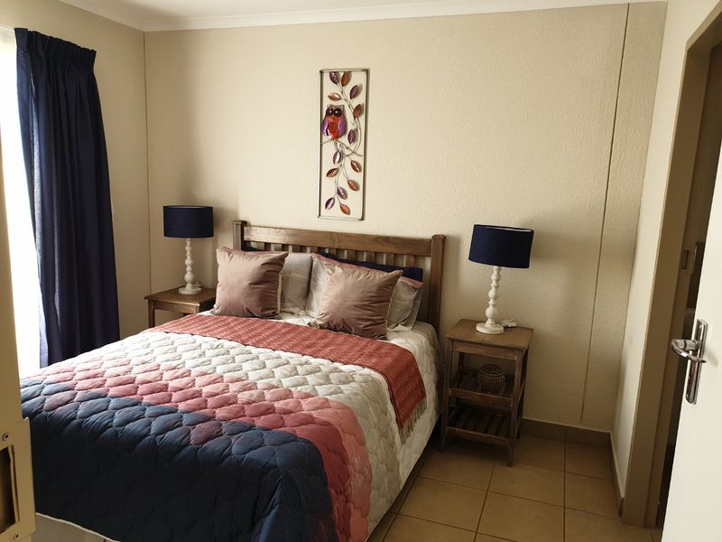 A functional bedroom featuring neutral wall finishes, tiled flooring, and classic cove cornicing, providing a comfortable and well-maintained living space.