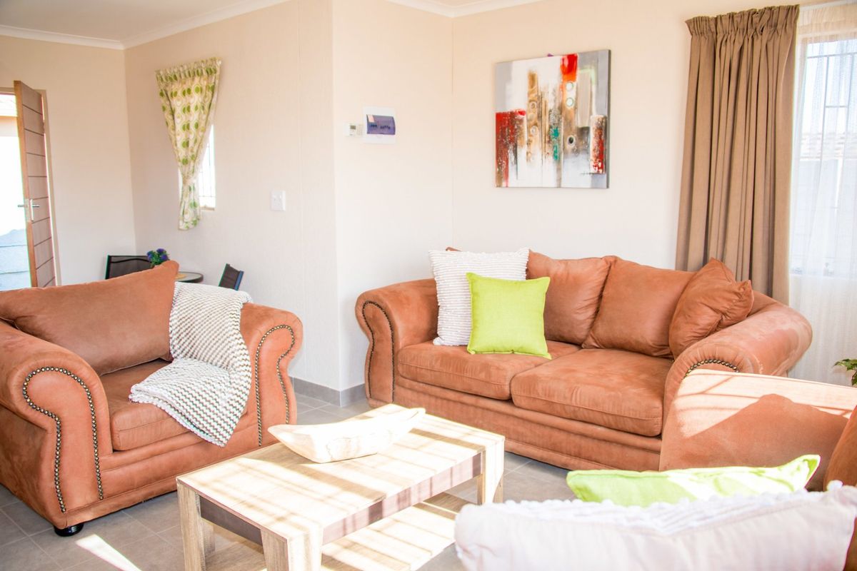 A bright and comfortable living room featuring neutral tiled flooring and classic cove cornicing, providing a functional and inviting space.