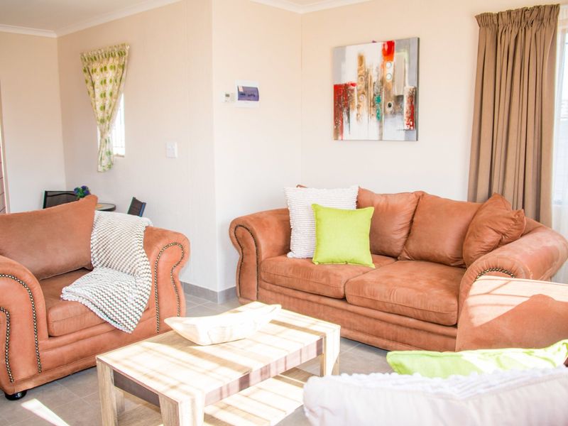 A bright and comfortable living room featuring neutral tiled flooring and classic cove cornicing, providing a functional and inviting space.
